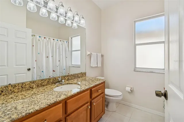 a bathroom with a granite countertop sink a toilet and a mirror