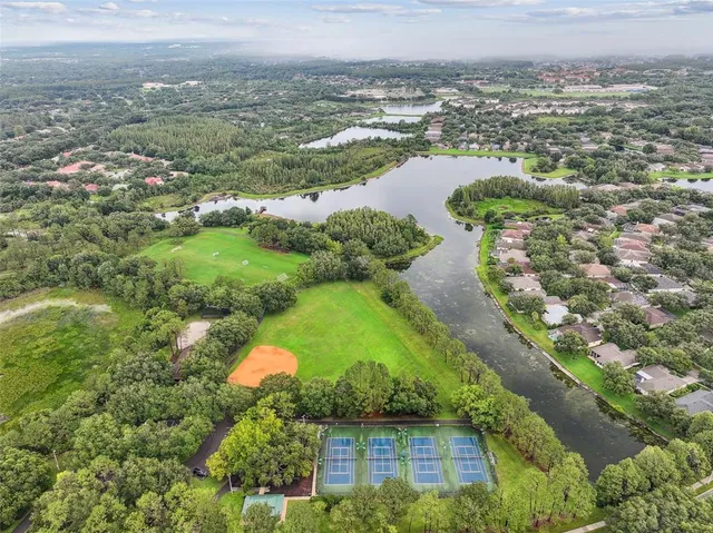 an aerial view of a residential houses with outdoor space and trees all around