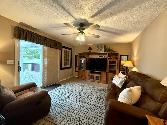 a living room with furniture a ceiling fan and a flat screen tv