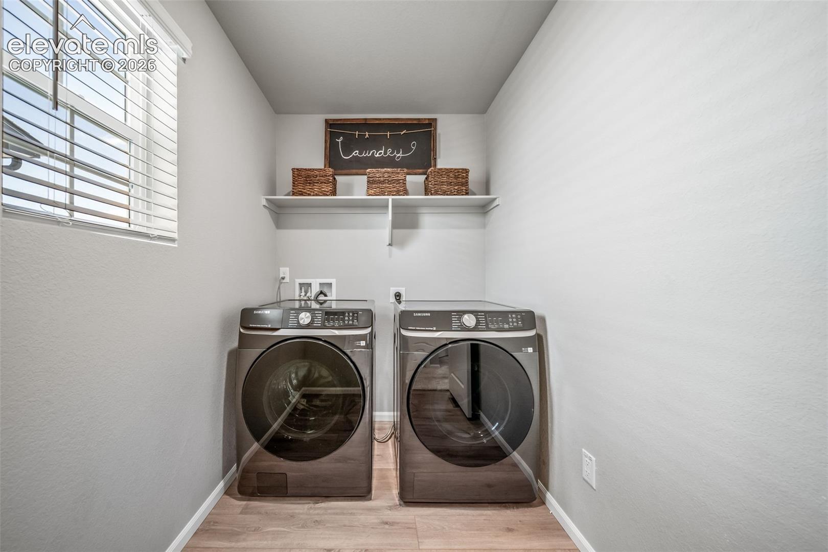 4866 Truscott Road Colorado Springs, CO 80925 - Photo 15 of 20 Dedicated laundry area featuring wood-finish flooring, a window with blinds, and a built-in wall shelf
*Photos of a model home*