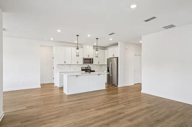 a kitchen with stainless steel appliances granite countertop a sink a stove and a wooden floors