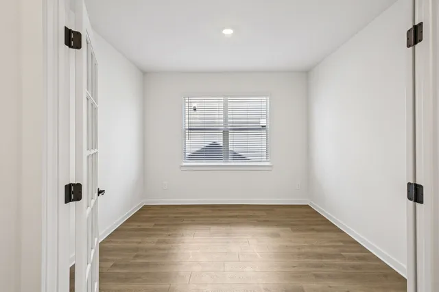 an empty room with wooden floor and a window