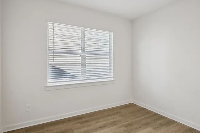 an empty room with wooden floor & closet area