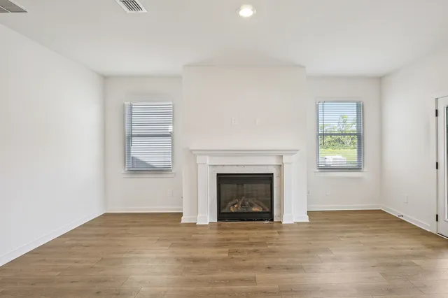 a view of a kitchen with wooden floor a ceiling fan and windows
