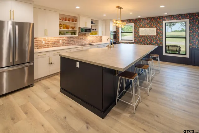 a kitchen with stainless steel appliances granite countertop a refrigerator a stove and a wooden floors