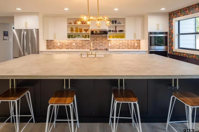 a large kitchen with stainless steel appliances kitchen island granite countertop a table and chairs in it