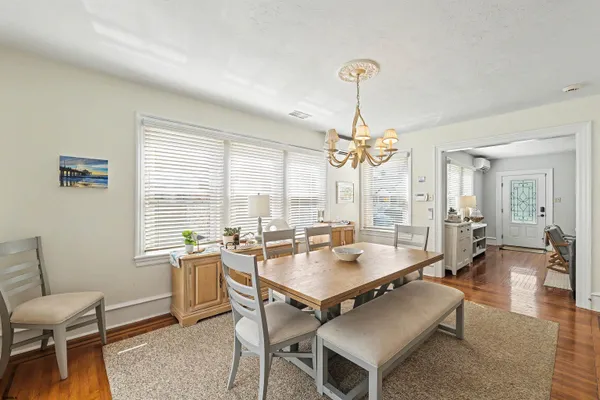 a dining room with wooden floor a chandelier a wooden table and chairs