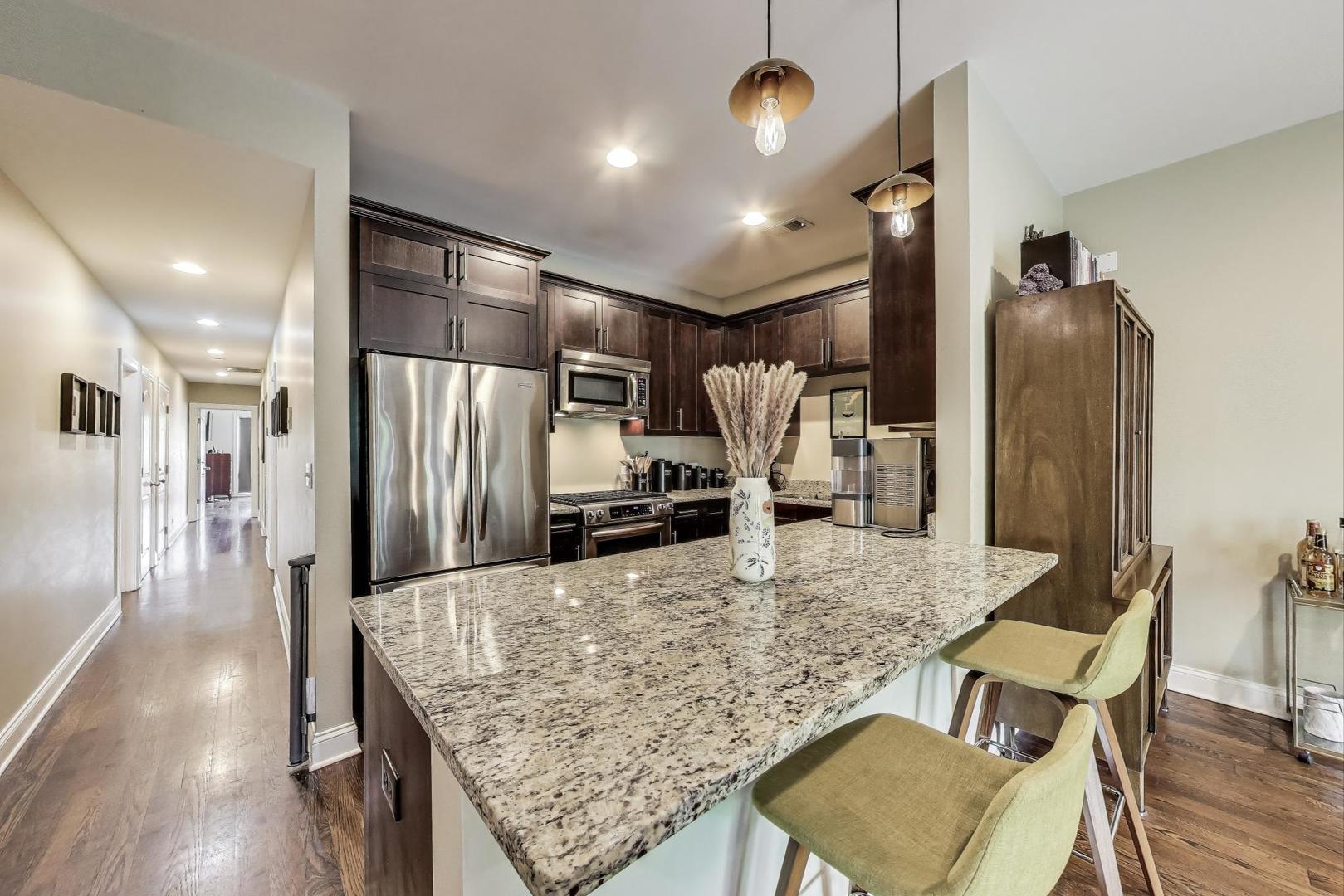 2120 West Rice Street, Unit 3 Chicago, IL 60622 - Photo 10 of 28 a kitchen with stainless steel appliances kitchen island granite countertop a refrigerator a stove and white cabinets with wooden floor