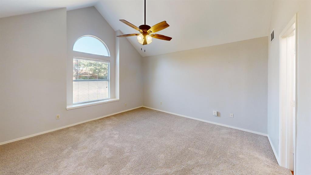 7913 Rice Drive Rowlett, TX 75088 - Photo 13 of 25 Carpeted room featuring a vaulted ceiling with an arched transom window, a ceiling fan with light fixture, and neutral wall paint