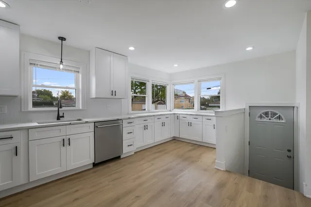 a kitchen with white cabinets and wooden floors