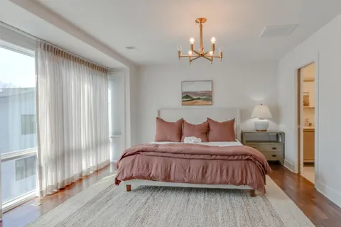 a bedroom with a bed chandelier and a window