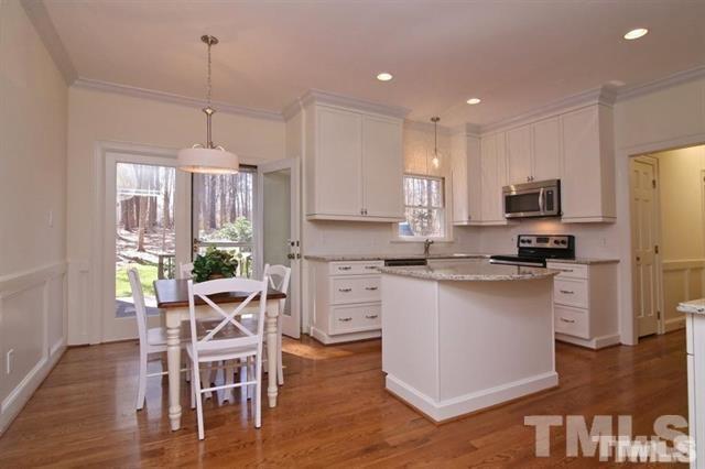 805 Thatcher Way Raleigh, NC 27615 - Photo 8 of 25 a kitchen with stainless steel appliances granite countertop a stove top oven a refrigerator a sink and a dining table with wooden floor