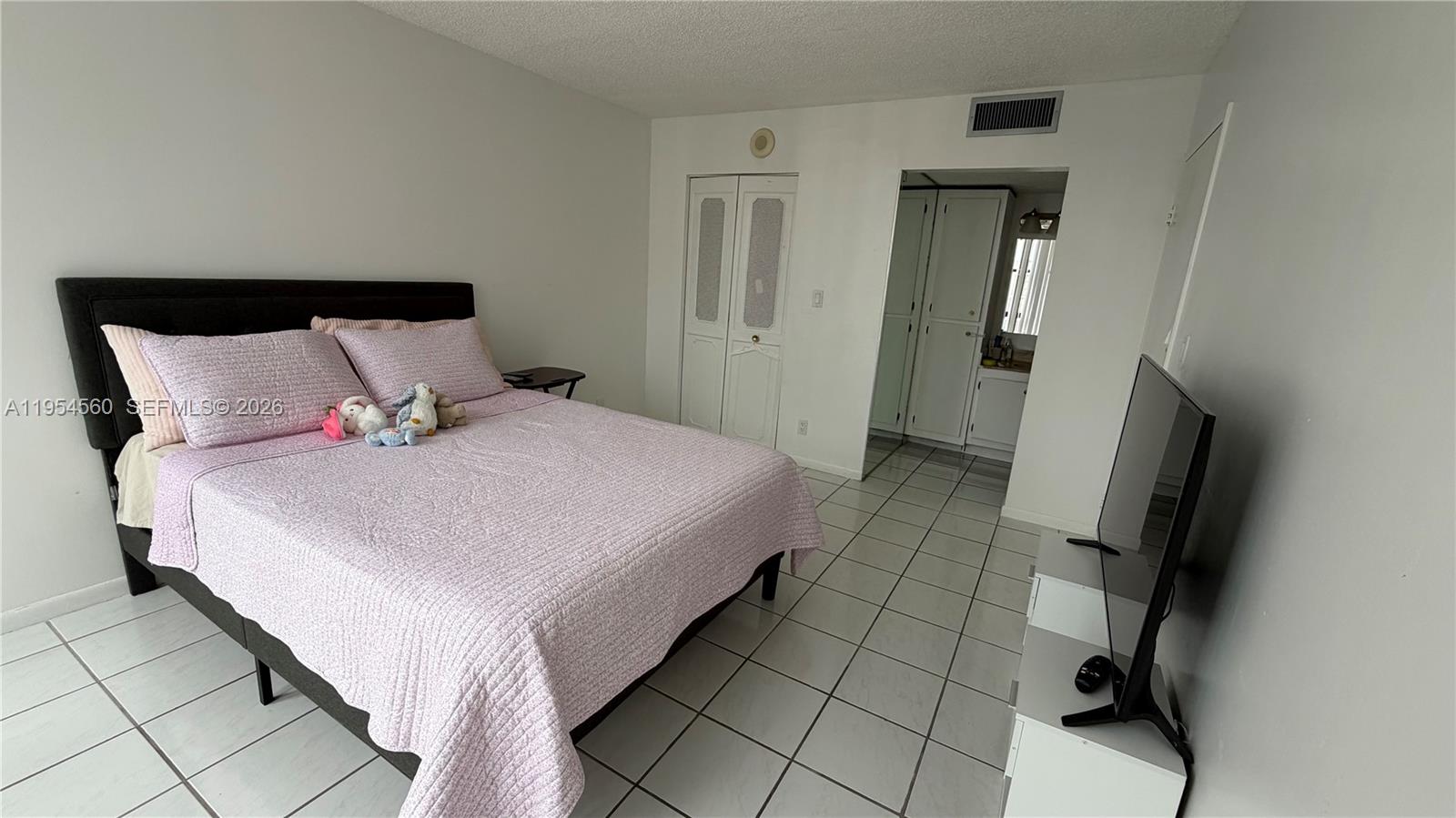 17011 North Bay Road, Unit 912 Sunny Isles Beach, FL 33160 - Photo 25 of 43 a bedroom with a bed and a flat tv screen on a dresser