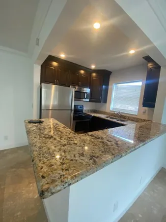 a large kitchen with kitchen island a sink appliances and a counter top space