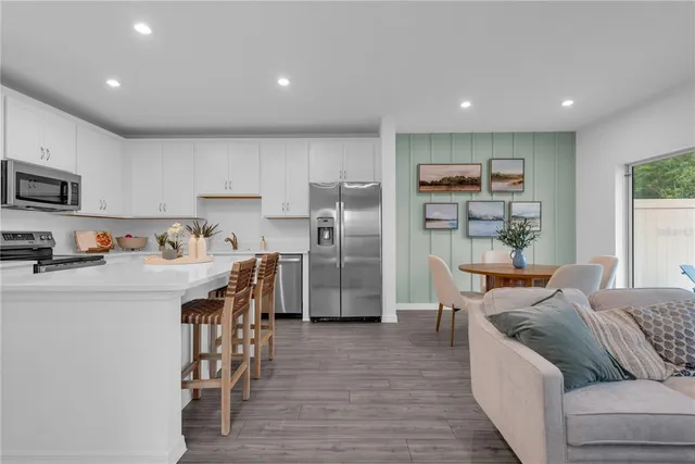 a kitchen with stainless steel appliances granite countertop a refrigerator a stove top oven a sink dishwasher and white cabinets with wooden floor