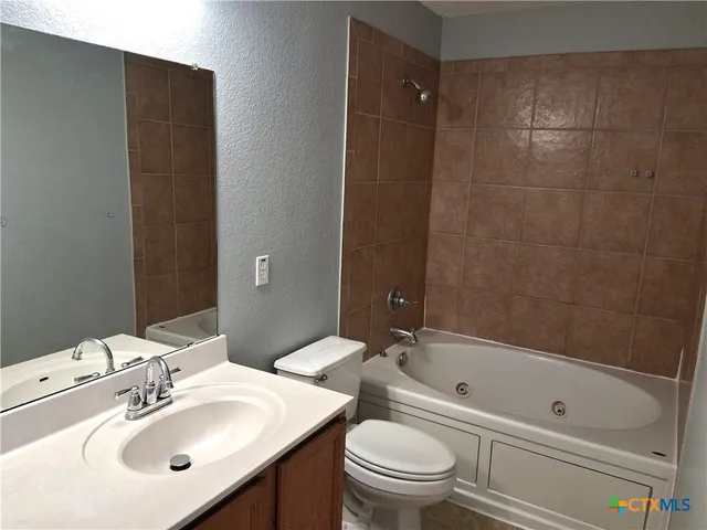 a bathroom with a bathtub shower sink vanity mirror and toilet