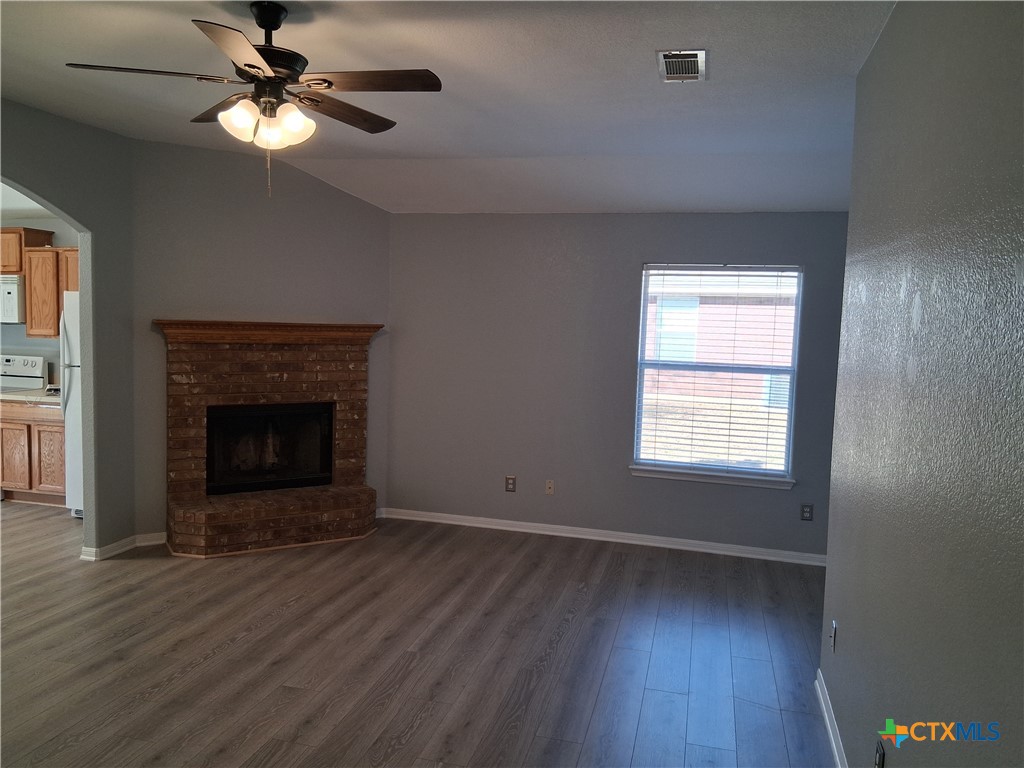5605 Bald Ridge Court Killeen, TX 76542 - Photo 5 of 17 an empty room with wooden floor a chandelier fan and a fireplace