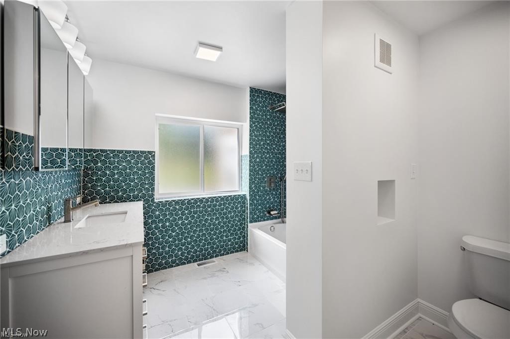 28300 Aurora Road Solon, OH 44139 - Photo 7 of 36 Contemporary bathroom featuring a dual vanity with undermount sinks, a white bathtub, and a tiled shower surround
