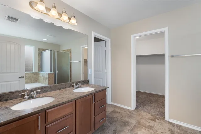 a spacious bathroom with a granite countertop sink a mirror and a shower