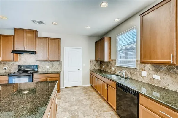 a large kitchen with stainless steel appliances granite countertop a sink stove and cabinets