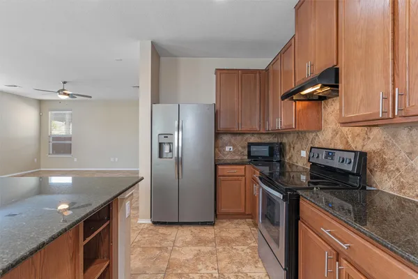 a kitchen with stainless steel appliances granite countertop a sink a stove and a refrigerator