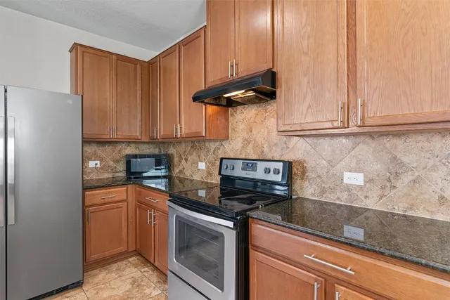 a kitchen with stainless steel appliances granite countertop a refrigerator and a stove top oven