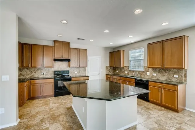 a kitchen with stainless steel appliances granite countertop sink stove top oven and granite counter top