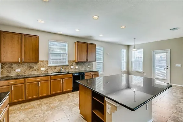 a large kitchen with stainless steel appliances granite countertop a sink a stove counter space and cabinets