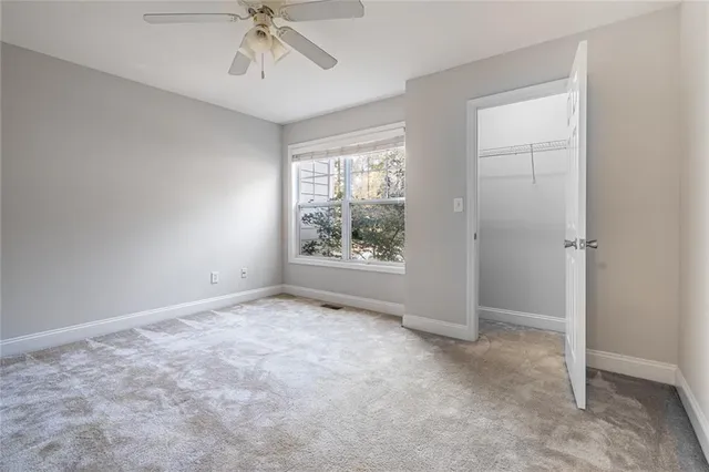 an empty room with a ceiling fan and carpet