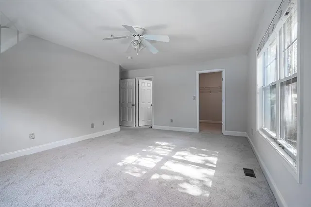 an empty room with windows and ceiling fan