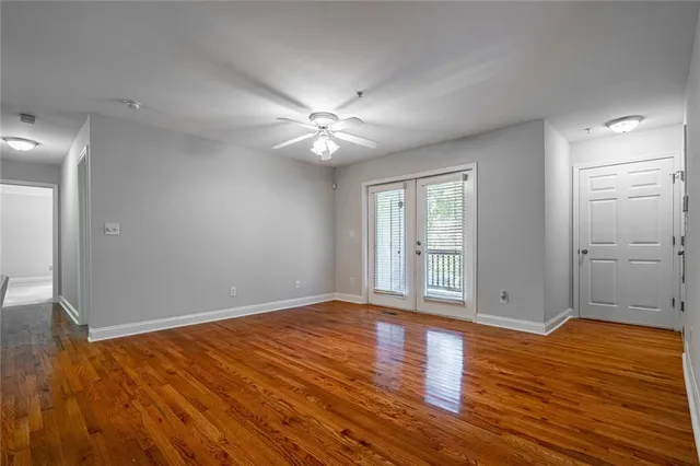a view of an empty room with wooden floor and a window