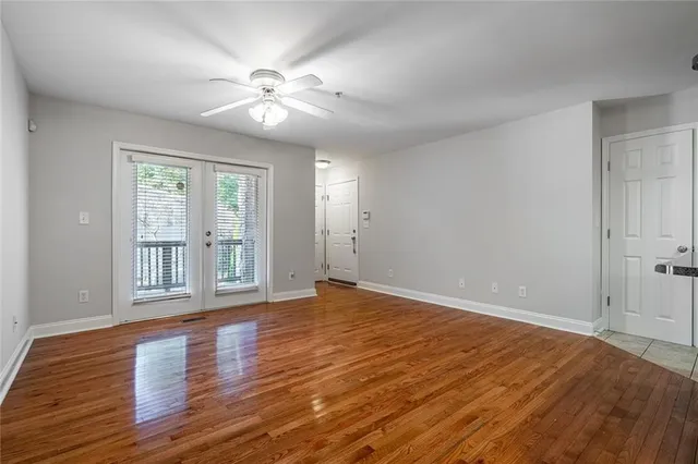 an empty room with wooden floor and kitchen view