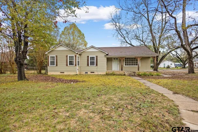 a front view of a house with a garden and trees