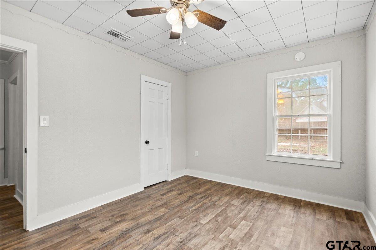 2707 Dudley Road Kilgore, TX 75662 - Photo 16 of 29 an empty room with wooden floor chandelier fan and windows