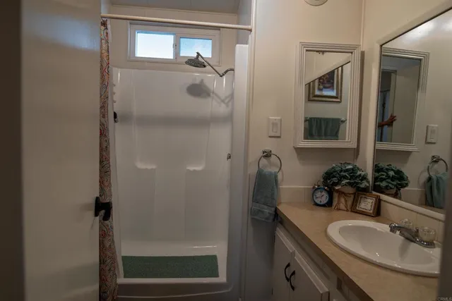 a bathroom with a granite countertop shower sink and mirror