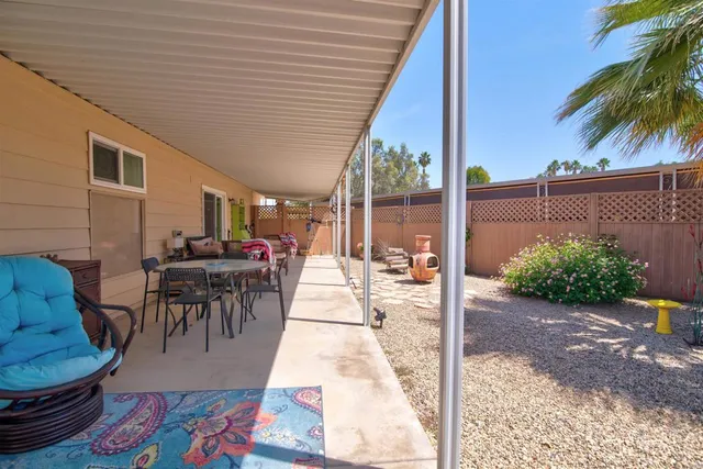a view of a patio with table and chairs potted plants and palm tree