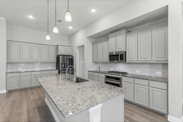 a kitchen with stainless steel appliances granite countertop a sink refrigerator and cabinets