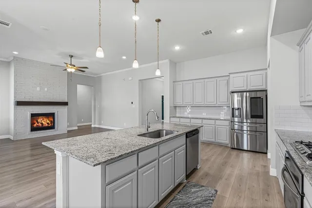a kitchen with kitchen island granite countertop a sink a counter top space stainless steel appliances and cabinets