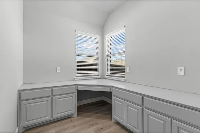 a workspace with white cabinets and a window