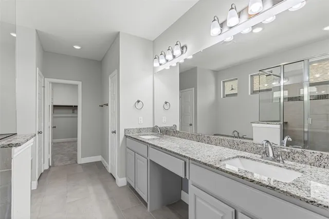 a bathroom with a granite countertop double vanity sink and a mirror