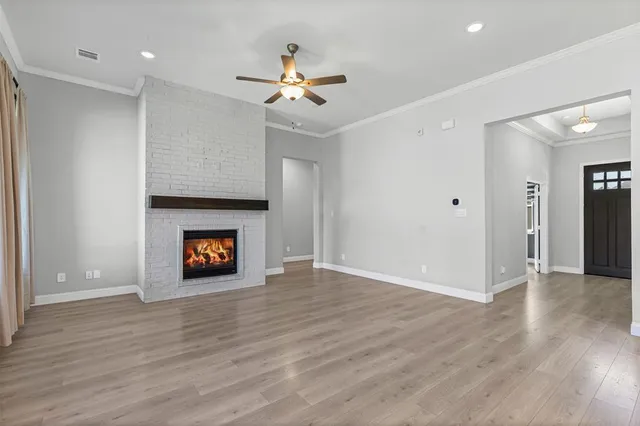 a view of an empty room with wooden floor and a fireplace