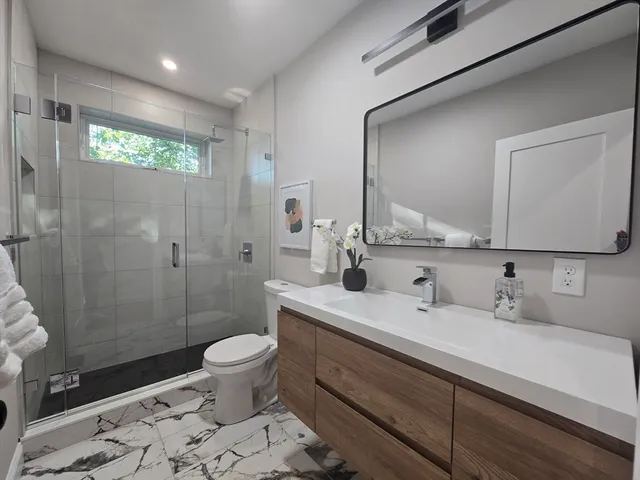 a bathroom with a sink a toilet and shower