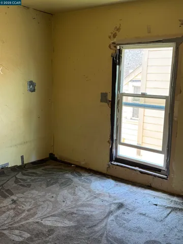 a view of an empty room with wooden floor and windows