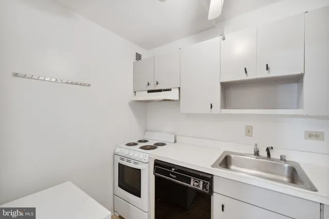 a kitchen with a sink a refrigerator and white cabinets