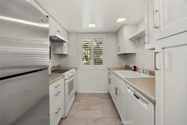 a kitchen with granite countertop a sink stove and refrigerator