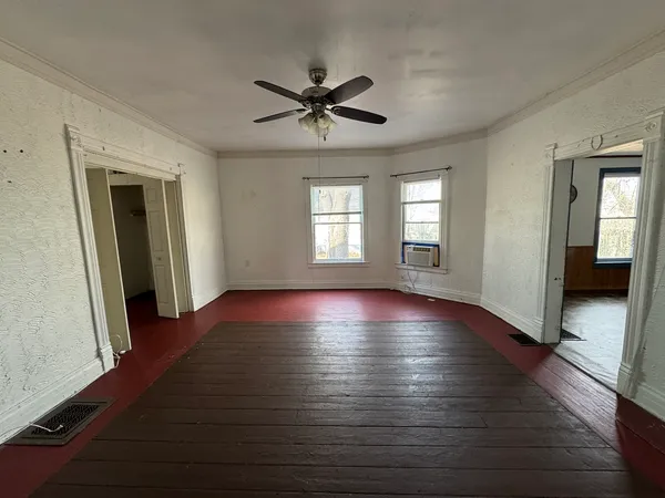 a view of empty room with wooden floor and fan