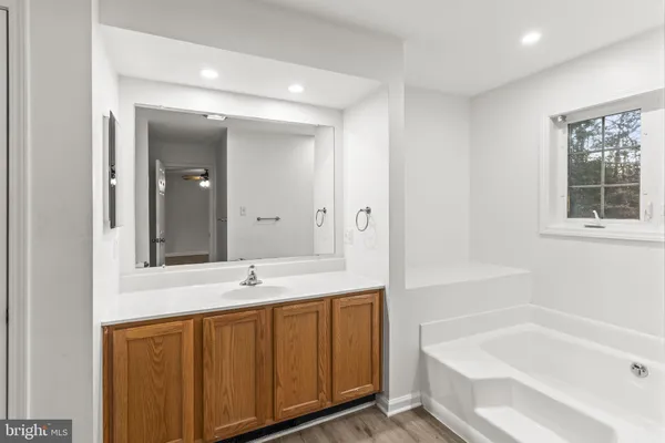 a bathroom with a tub sink and mirror