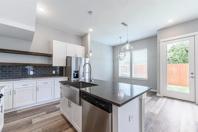 a kitchen that has a lot of white cabinets and wooden floor
