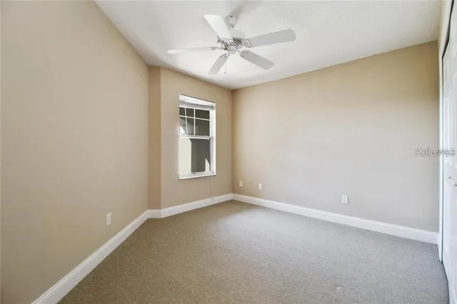 an empty room with windows and ceiling fan