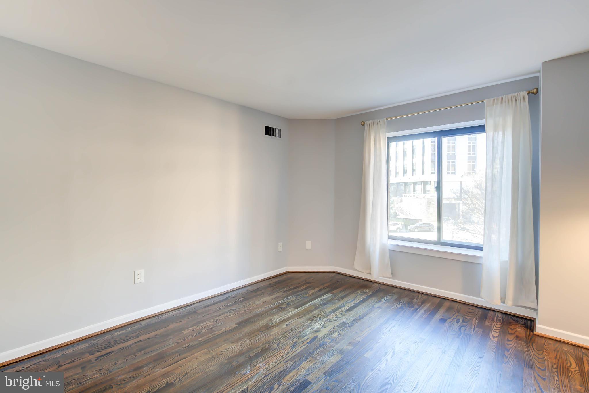 2111 Wisconsin Avenue Northwest, Unit 302 Washington, DC 20007 - Photo 13 of 23 an empty room with wooden floor and window